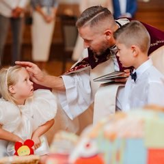 Kunigas bažnyčioje laimina mergaitę ir berniuką baltais drabužiais – Donatos Jankauskės fotografija, Šiauliai