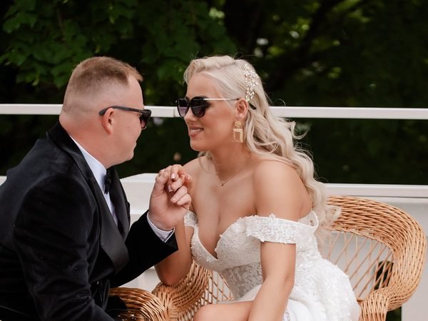 Jaunikis bučiuoja nuotakos ranką sėdėdami terasoje – vestuvių fotosesija Šiauliuose