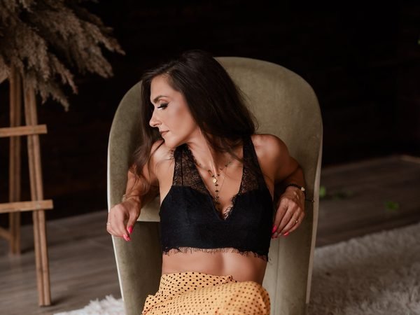 Moteris juoda nėriniuota liemenėle sėdi fotelyje – asmeninė fotosesija Šiauliuose