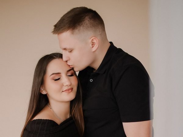 Pora studijoje, vyras švelniai bučiuoja moterį į kaktą – laukimo fotosesija Šiauliuose