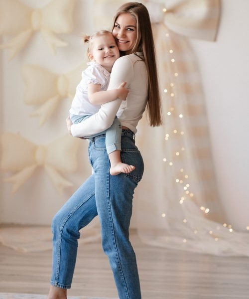 Mama nešioja mažą dukrytę ant rankų, abi šypsosi – šeimos fotosesija Šiauliuose