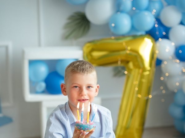 Berniukas laiko keksiuką su žvakutėmis prie balionų puošybos – cake smash fotosesija Šiauliuose