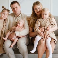 Vyresnioji dukra laiko kūdikį tėvų glėbyje sofoje vienodais rūbais – Donatos Jankauskės fotografija, Šiauliai