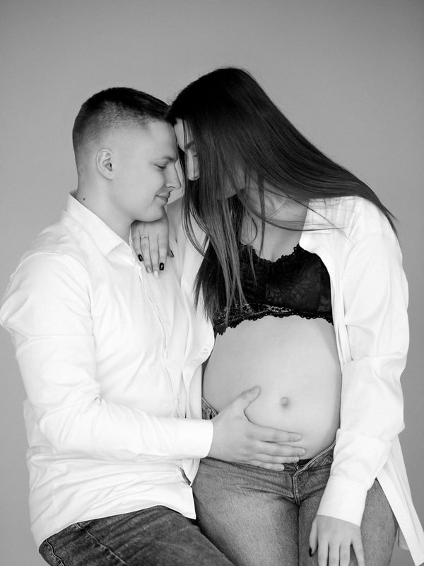 Nėščios moters ir vyro portretas juodai baltai, vyras prilaiko pilvuką – laukimo fotosesija Šiauliuose