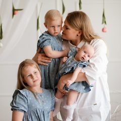 Mama su trimis dukromis pozuoja studijoje, kabo gėlių girliandos fonas – Donatos Jankauskės fotografija, Šiauliai