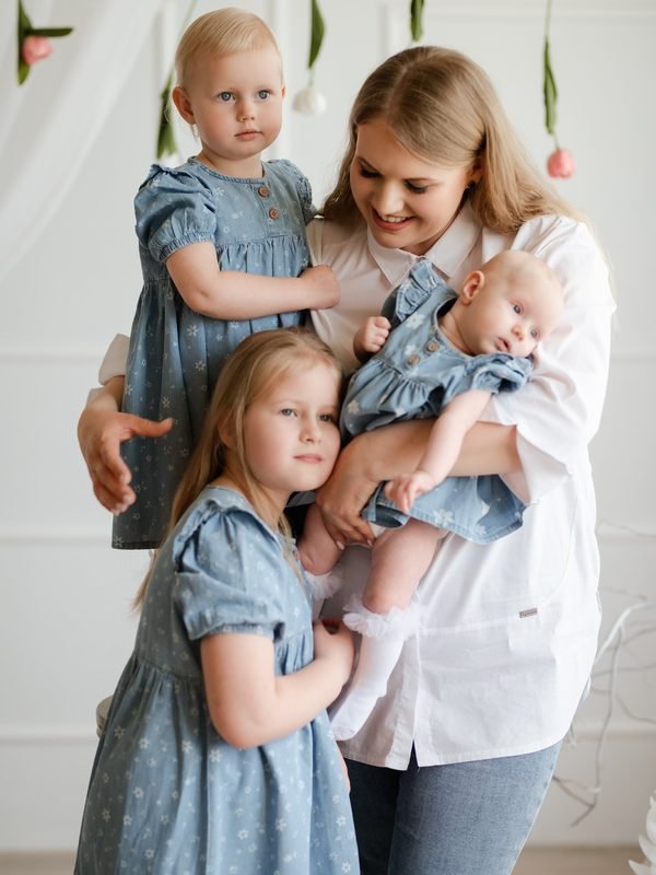 Mama su trimis dukromis vienodomis melsvomis suknelėmis studijoje – šeimos fotosesija Šiauliuose